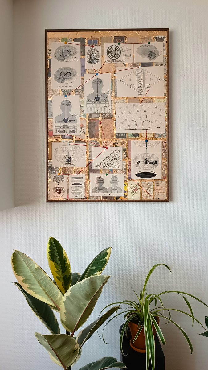 Het ingelijste werk aan een witte muur, met planten ervoor.